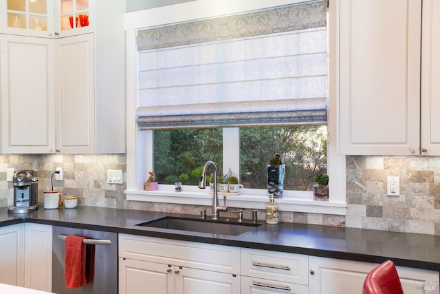 kitchen with a sink, white cabinetry, backsplash, and dark countertops