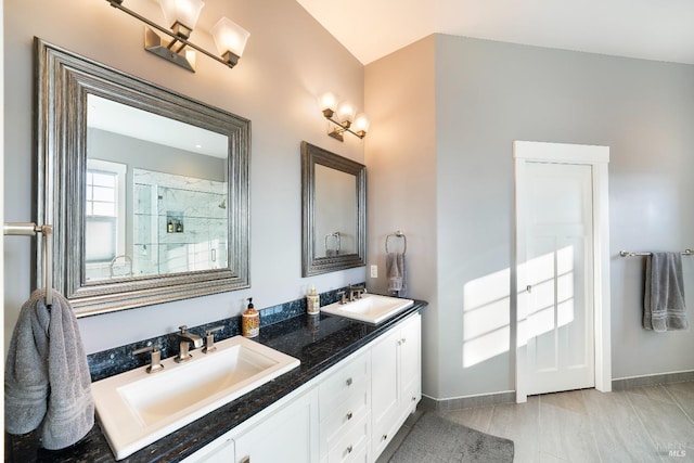 bathroom featuring a sink, baseboards, an enclosed shower, and double vanity