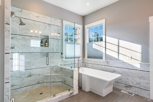 full bath featuring a marble finish shower, recessed lighting, tile walls, visible vents, and a soaking tub
