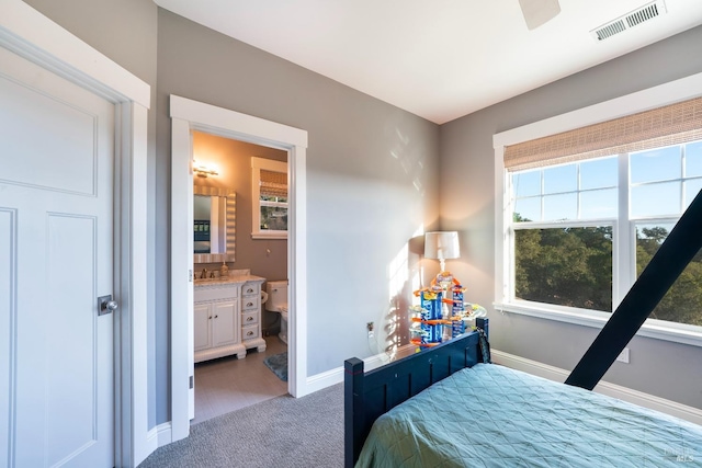 carpeted bedroom featuring visible vents, a sink, baseboards, and ensuite bathroom