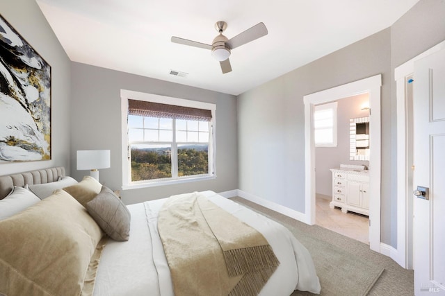 bedroom with a ceiling fan, light colored carpet, visible vents, baseboards, and connected bathroom