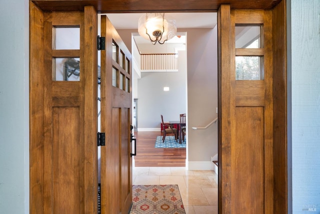 foyer entrance with an inviting chandelier, baseboards, and light tile patterned flooring