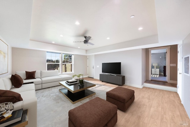 living area featuring recessed lighting, ceiling fan, a tray ceiling, and light wood finished floors