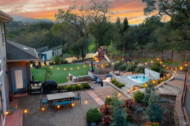 exterior space featuring outdoor dining area, a fenced backyard, a patio area, a playground, and an outdoor fire pit