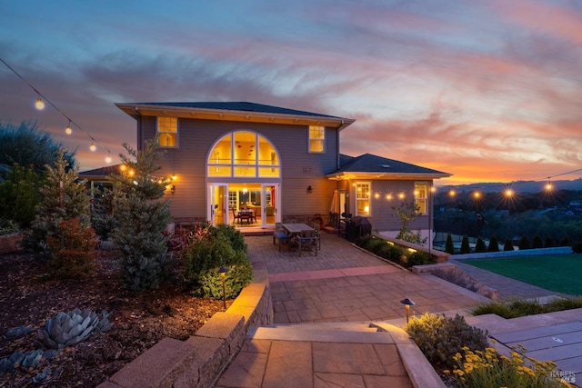 back of property at dusk featuring a patio