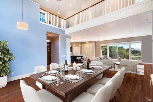 dining area with baseboards, a high ceiling, and wood finished floors