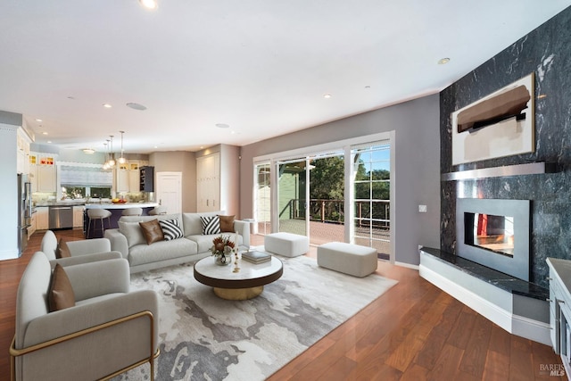 living area featuring dark wood-type flooring, a high end fireplace, baseboards, and recessed lighting