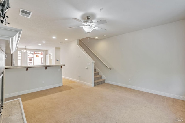 unfurnished living room with ceiling fan with notable chandelier, visible vents, recessed lighting, light carpet, and baseboards