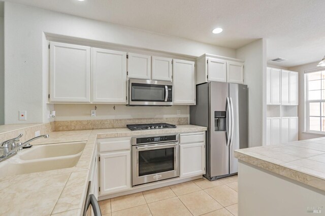kitchen with light tile patterned floors, white cabinets, visible vents, appliances with stainless steel finishes, and a sink