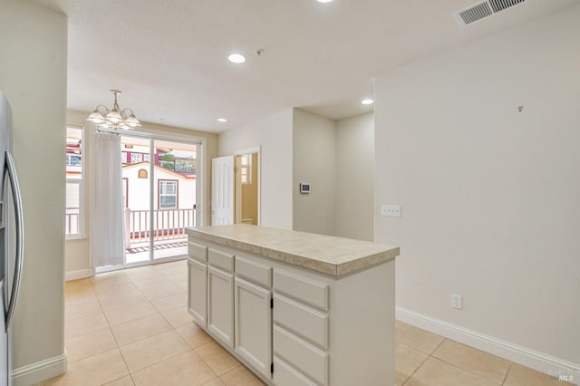 kitchen with visible vents, light countertops, a kitchen island, and light tile patterned flooring