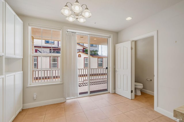 doorway featuring an inviting chandelier, baseboards, and light tile patterned floors