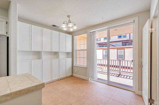 unfurnished dining area featuring light tile patterned floors, visible vents, baseboards, and an inviting chandelier