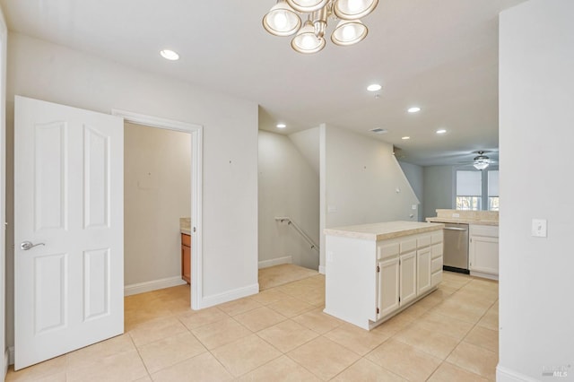 kitchen featuring stainless steel dishwasher, light tile patterned floors, light countertops, and white cabinetry