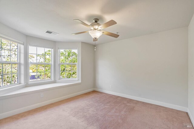 unfurnished room featuring visible vents, light colored carpet, baseboards, and ceiling fan