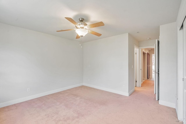spare room featuring light carpet, baseboards, and ceiling fan
