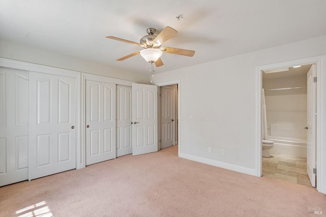 unfurnished bedroom with baseboards, two closets, connected bathroom, and carpet floors