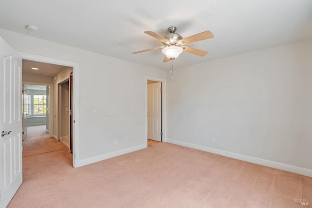 empty room featuring light colored carpet, baseboards, and a ceiling fan