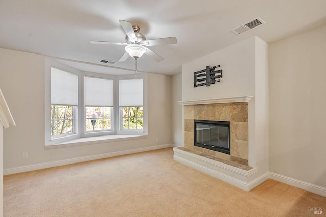 unfurnished living room with baseboards, a tiled fireplace, and visible vents