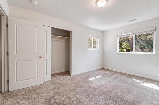 unfurnished bedroom with visible vents, baseboards, a closet, and light colored carpet