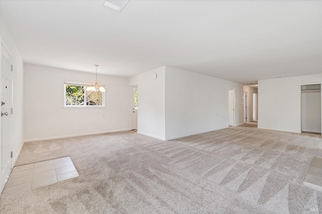 unfurnished living room with baseboards, light carpet, a notable chandelier, and visible vents