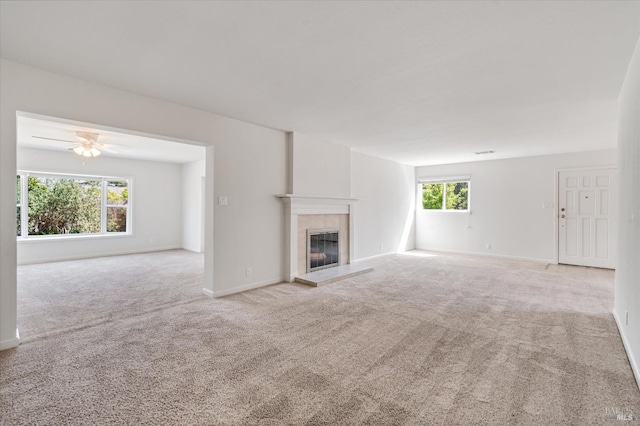 unfurnished living room with baseboards, carpet, a ceiling fan, and a tile fireplace