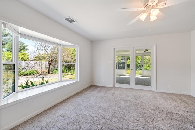 carpeted empty room featuring a ceiling fan, baseboards, visible vents, and french doors