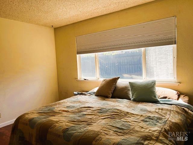 bedroom with baseboards, multiple windows, and a textured ceiling