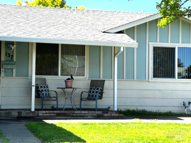 view of side of property with roof with shingles and covered porch