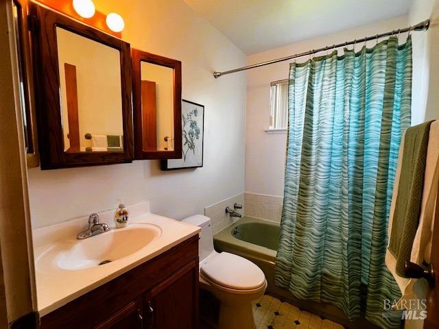 full bathroom with toilet, shower / bath combo with shower curtain, vaulted ceiling, and vanity