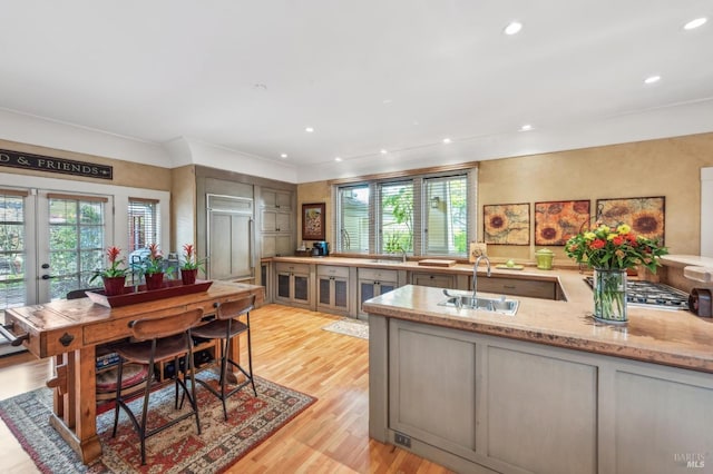 kitchen featuring french doors, recessed lighting, light stone counters, light wood finished floors, and a sink