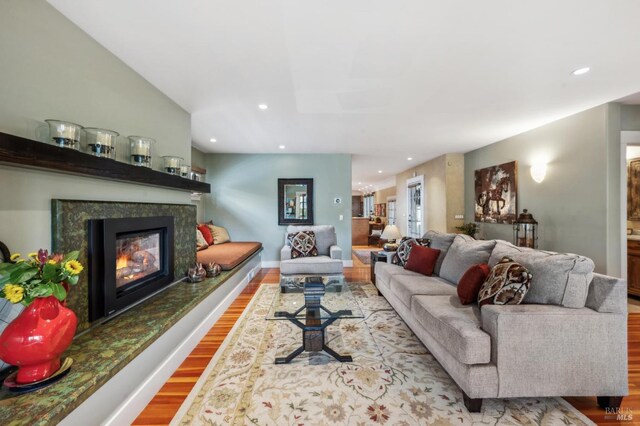 living area with recessed lighting, wood finished floors, baseboards, and a glass covered fireplace