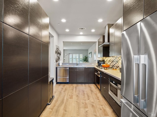 kitchen with a sink, light wood-style floors, tasteful backsplash, visible vents, and appliances with stainless steel finishes