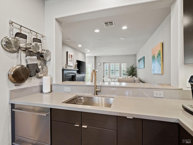 kitchen with visible vents, light countertops, dark brown cabinets, and a sink