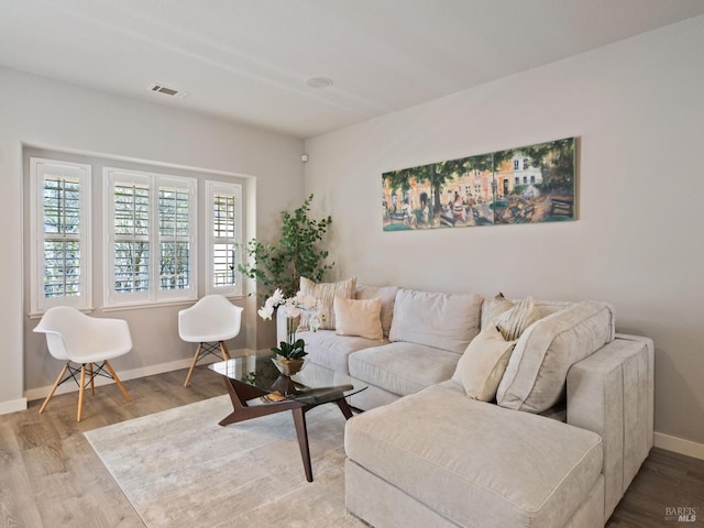 living area featuring wood finished floors, visible vents, and baseboards