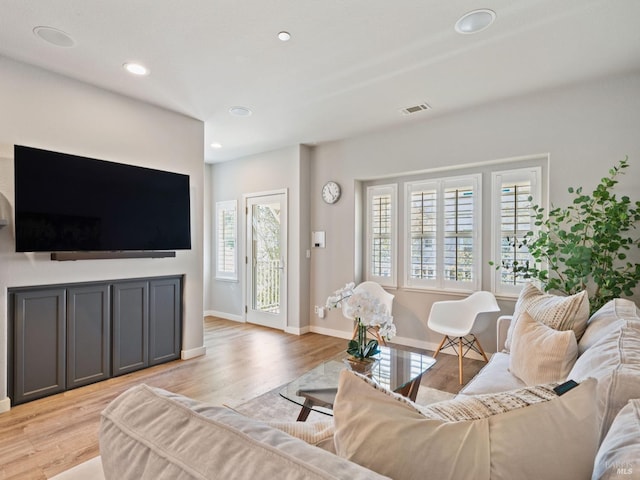 living area with light wood finished floors, visible vents, and a healthy amount of sunlight
