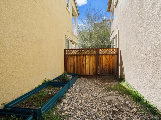 view of home's exterior with stucco siding, fence, and a gate