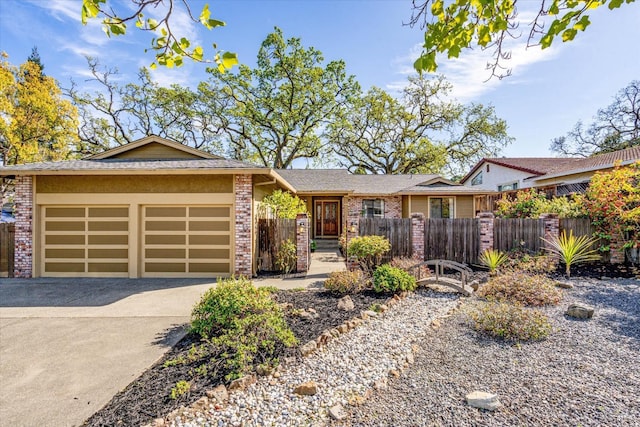 view of front of house featuring brick siding, an attached garage, fence, and driveway