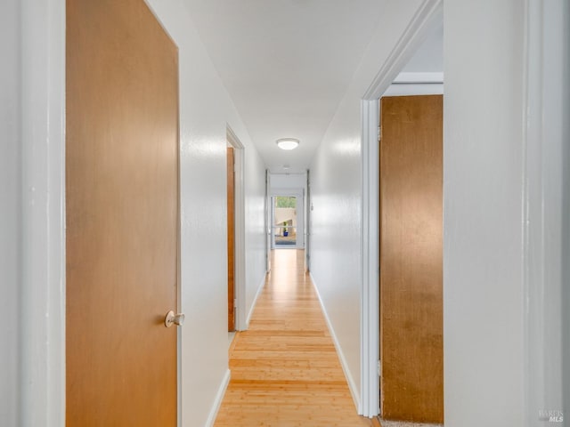corridor with light wood finished floors and baseboards