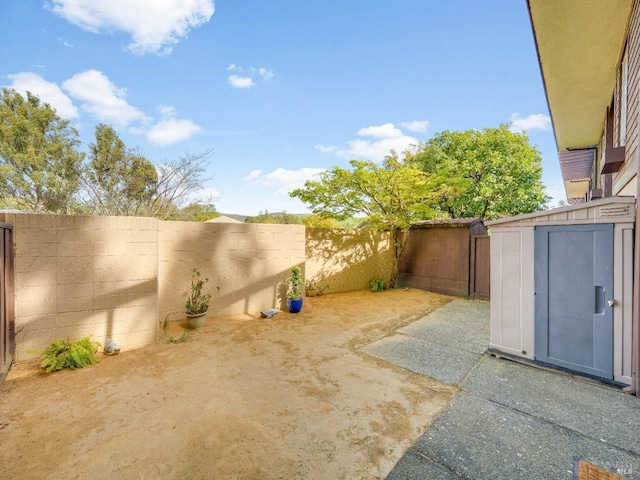 view of yard with an outbuilding, a shed, a fenced backyard, and a patio area