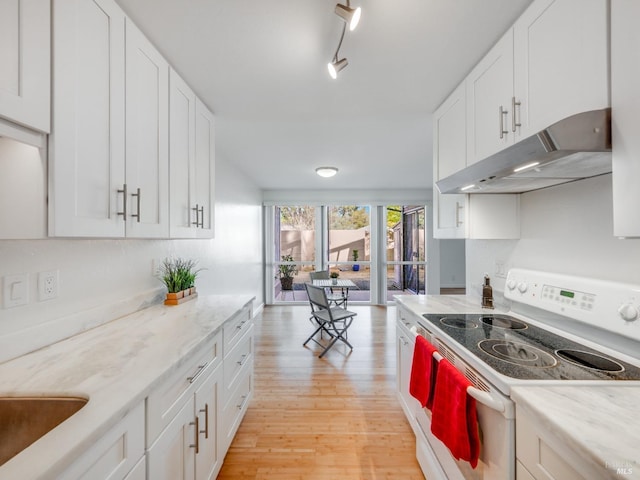 kitchen featuring light wood-type flooring, under cabinet range hood, white cabinetry, rail lighting, and electric range