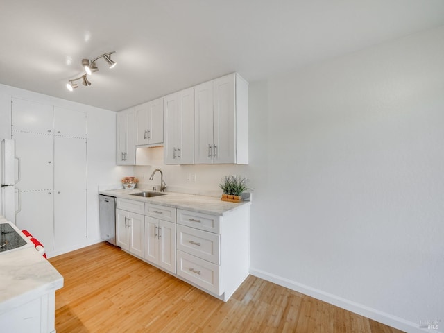 kitchen with white cabinets, baseboards, dishwasher, a sink, and light wood-style floors