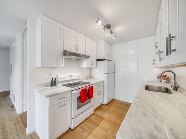 kitchen with white appliances, light wood-style flooring, white cabinetry, under cabinet range hood, and a sink