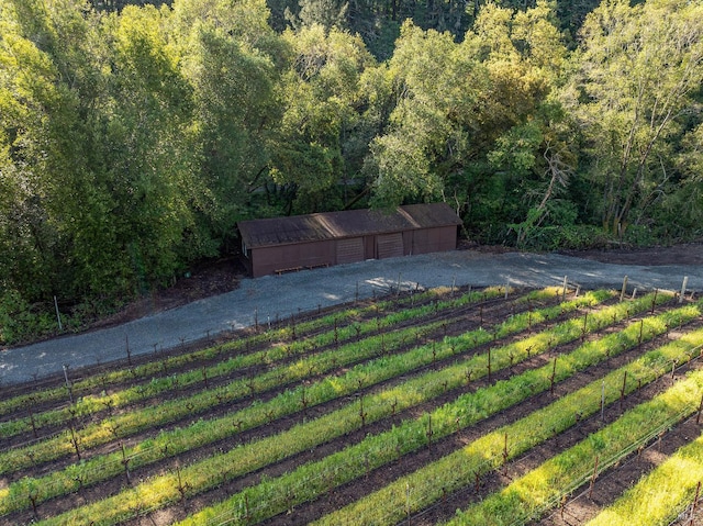 view of yard featuring an outdoor structure, a wooded view, fence, and a garage