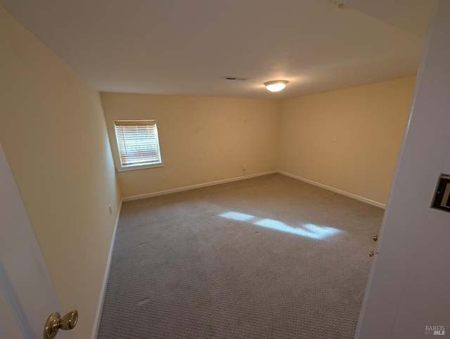 carpeted spare room with visible vents and baseboards