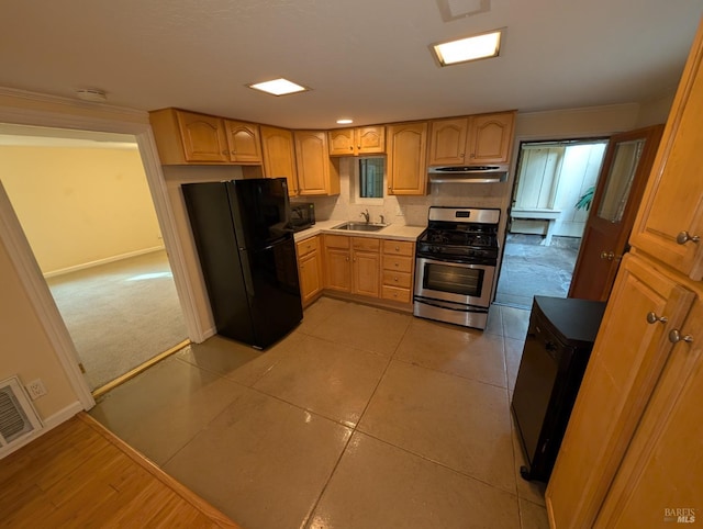 kitchen featuring black appliances, under cabinet range hood, visible vents, a sink, and light brown cabinetry