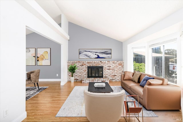 living area with wood finished floors, a brick fireplace, baseboards, and high vaulted ceiling