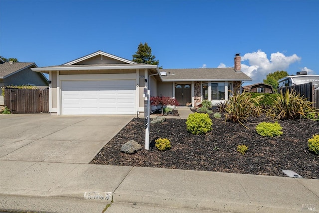 ranch-style house featuring fence, an attached garage, driveway, and a chimney