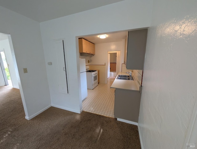 kitchen featuring baseboards, light countertops, white range with gas stovetop, light colored carpet, and a sink