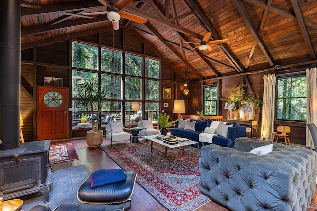 living area featuring a wood stove, wood-type flooring, wooden ceiling, a ceiling fan, and high vaulted ceiling