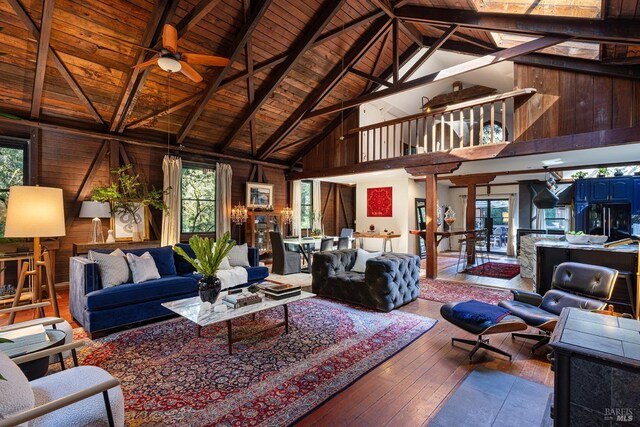 living area with wooden ceiling, hardwood / wood-style floors, a wealth of natural light, high vaulted ceiling, and a ceiling fan